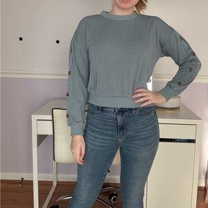 Blue crewneck sweatshirt with button details on the sleeves